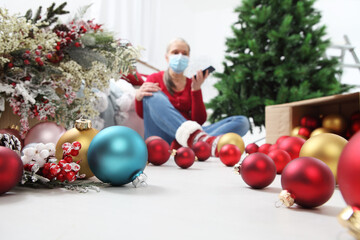 Merry christmas, woman wearing surgical mask is forced to stay at home alone due to coronavirus,...