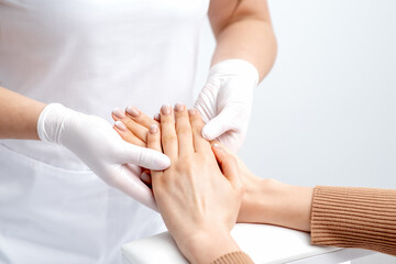 Obraz na płótnie Canvas Manicurist wearing gloves doing wax massage on female hands with manicure in nail salon