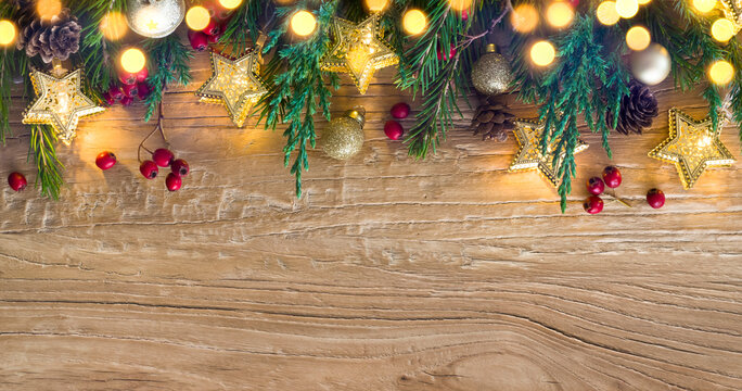Holiday garland lights with Christmas tree decoration on wood background