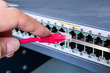 hand of network administrator plugging in network cable 