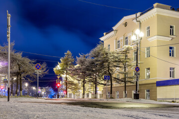 Night city landscape. Snow-covered empty street in the historical center of Magadan. Magadan region, Siberia, Far East of Russia. There is no one on the street.