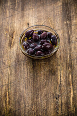 Small glass bowl with olives on a wooden rustic table. Selective focus - shallow depth of field.