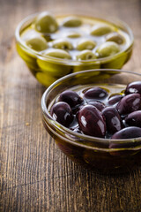 Small glass bowl with olives on a wooden rustic table. Selective focus - shallow depth of field.