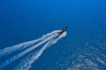 Speed boat movement at high speed aerial view. High-speed yacht of blue color fast motion on blue water in the rays of the sun top view.