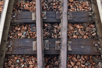 Oiled old rusty steel rails and sleepers on rubble