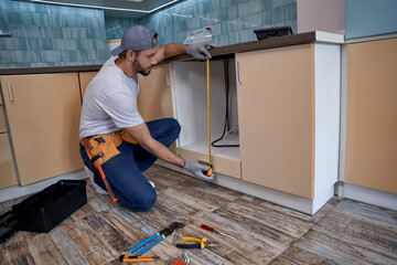 Young man measuring height of kitchen drawer
