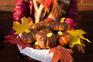 Homemade apple cakes in the shape of pumpkins, cosy colorful shawl or scarf and autumn leaves