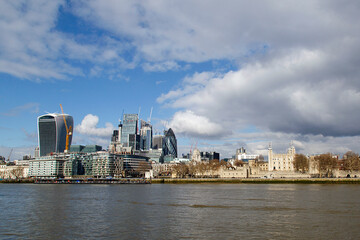View of the Tower of London alongside new construction on the north bank of the Thames River. City cruises pier is located on the promenade.