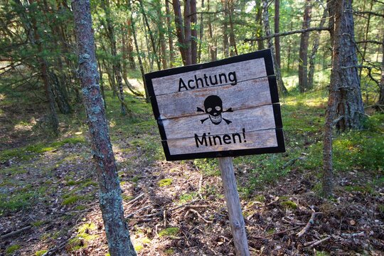 Signs warning of a minefield in the woods
