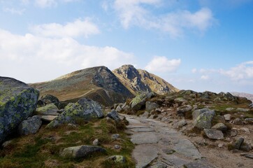 Fototapeta na wymiar Stone path on a mountain ridge with the tops of rocky mountains in the background 