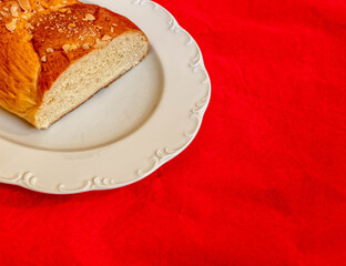 tsoureki, traditional Greek sweet bread served on white plate and red fabric background