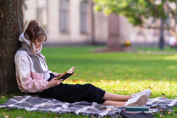 Young woman relaxing reading a book under a tree