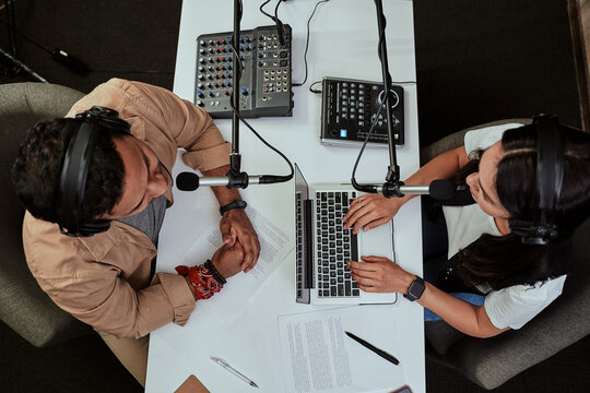 Top view of two radio hosts, young man and woman discussing various topics while moderating a live show in studio