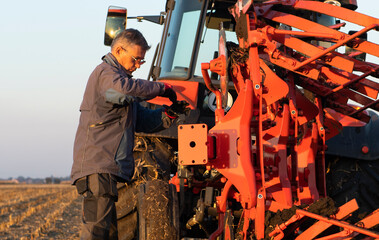  mechanic fixing plow on the tractor