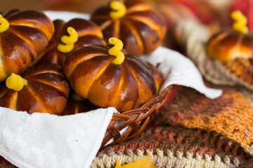 Homemade apple cakes in the shape of pumpkins, cosy colorful shawl or scarf and autumn leaves