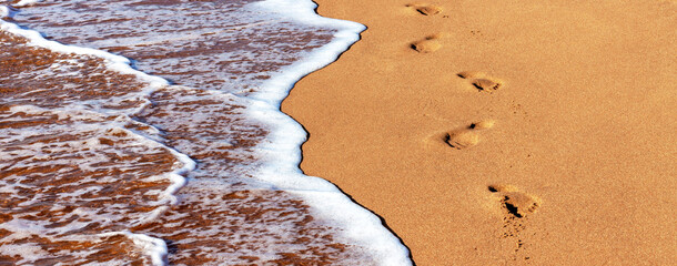 Close-up of the sea coast, clear sea water with shallow waves and white foam washes the shore with...