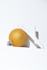 Minimal golden ball  with brunch decor in white trendy space. Fashion still life art. Merry Christmas / Happy New Year holidays celebration concept.