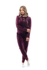 Young woman at home in leisure wear sweatsuit looking down contemplating. Full body isolated on white background.