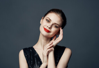 Charming lady in a black dress gestures with her hands on a gray background Copy Space