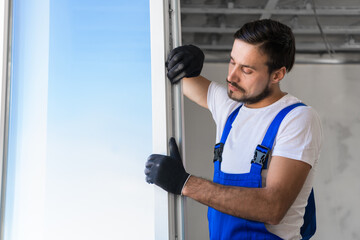 Bearded builder checks the plastic window in the apartment