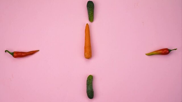 clock from vegetables moving arrows from carrots on a pink concrete background stop motion 