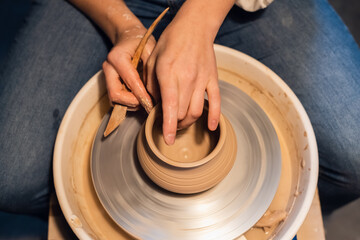 close-up of the hands of a potter when sculpting a vase from clay on a potter's wheel in the workshop