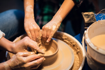 young mother and son sculpt clay dishes in a pottery workshop, close-up