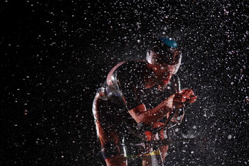 Fototapeta na wymiar triathlon athlete riding bike fast on rainy night