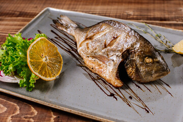 Smoked dorado fish with herbs on wooden background