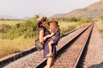 Mother with the daughter go on rails, back to a camera, on nature, in the summer