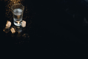 Vodka shots with ice on black table, copy space