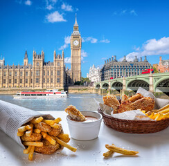 Big Ben against fish and chips served on the table in London, United Kingdom
