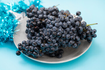 small grapes on dish on blue background and with Christmas decoration