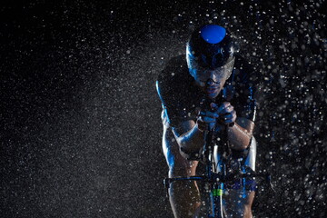 triathlon athlete riding bike fast on rainy night