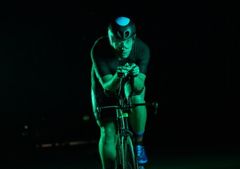 triathlon athlete riding bike fast at night