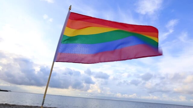 LGBT flag blown by the wind at seaside representing love and freedom. 