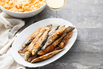 fried small sardines with tomato rice on white dish on ceramic background