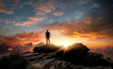 A man standing at the top of a mountain as the sun begins to set. Goals, hopes and aspirations...