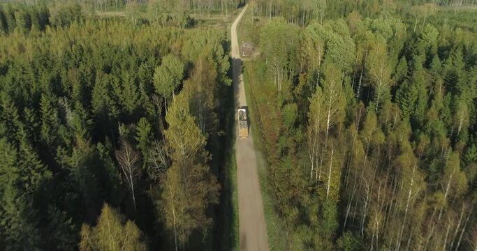 Logging truck with cut tree logs timber driving in forest on road aerial view