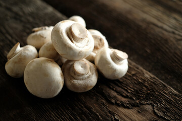 Fresh champignon mushrooms on wooden table, closeup. Space for text