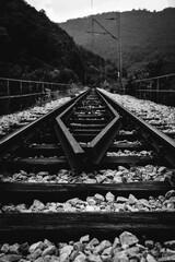 Two railway tracks merge together. Black and white photo of old railway 