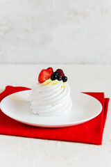 Dessert cake Pavlova with berries on a red napkin.