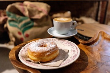 cup of coffee and bun, donut in italian coffee bar in Venezia, Venice, Italy. Cappuccino and ciambella on wooden tish, coffee grain bags on the background