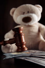 Payments alimony. Wooden judge gavel, money banknotes and teddy bear close-up. Divorce and alimony concept.
