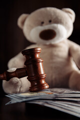 Payments alimony. Wooden judge gavel, money banknotes and teddy bear close-up. Divorce and alimony...
