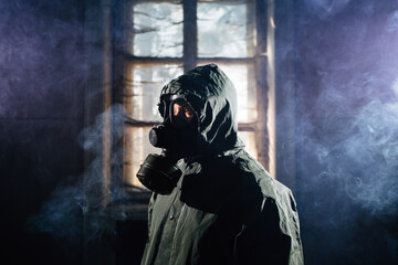 Spooky person with gas mask holding a lamp in dense fog in an abandoned building with eerie feeling. 