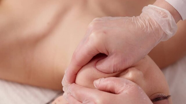cosmetologist makes a buccal massage of the patient's facial muscles.