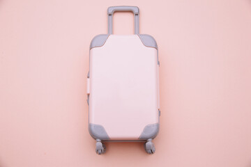 Mini travel luggage suitcase on pink background. Travel, beach, vacation concept.