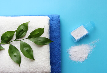 Two towels with green leaves on a blue background and washing powder.