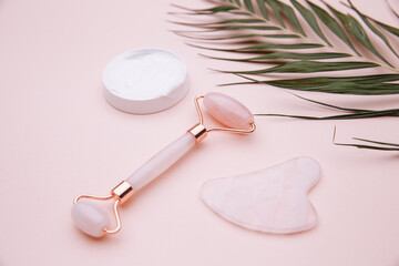 Rose quartz jade roller and gouache scraper on pink background. Anti age, lifting and toning...